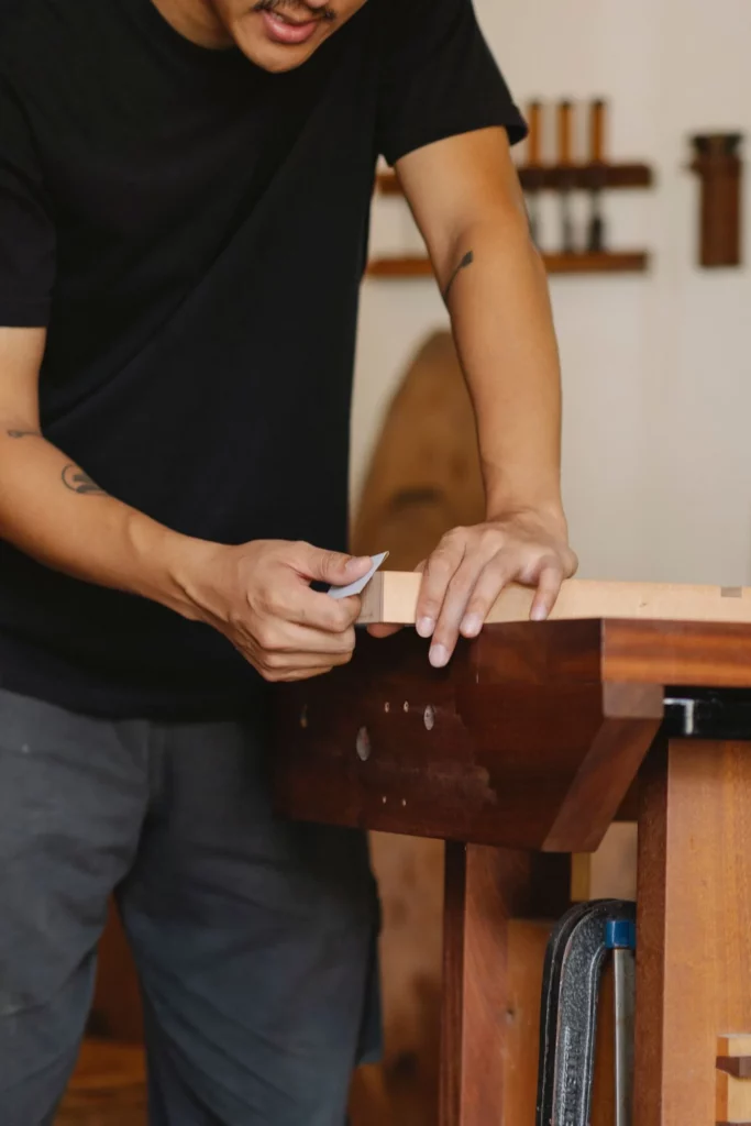 Artesão lixando peça de madeira em oficina