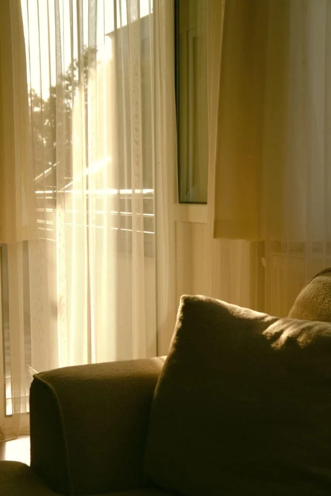 Cortinas claras instaladas ao lado de um sofá