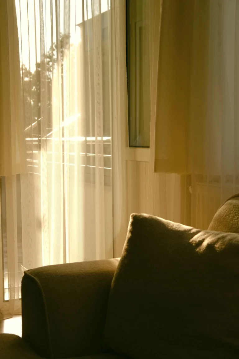 Cortinas claras instaladas ao lado de um sofá